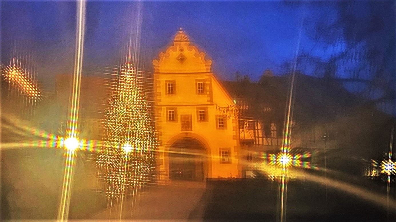 Weihnachtliche Beleuchtung beim Blick durch eine Gardine